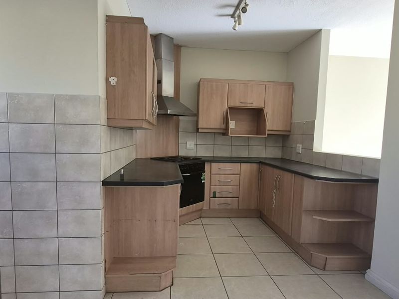 A functional kitchen featuring laminate cabinetry, built-in oven, extractor fan, and tiled flooring, requiring minor repairs and cosmetic updates.