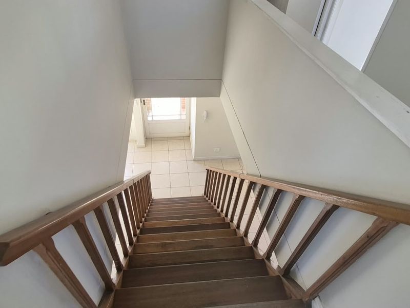 A view looking down a wooden staircase towards the tiled entrance area of the home.