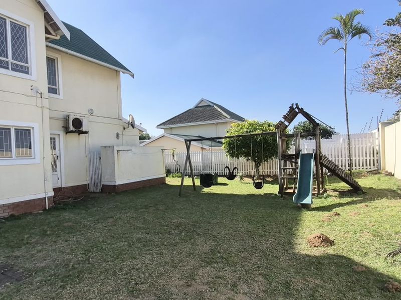 Rear garden area featuring a lawn, paved patio section, perimeter walling, and exterior access to the main dwelling.