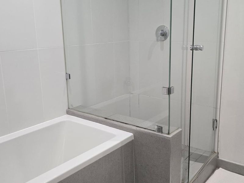 Modern bathroom featuring a clean white bathtub, a separate glass-enclosed shower, and neutral wall tiling.