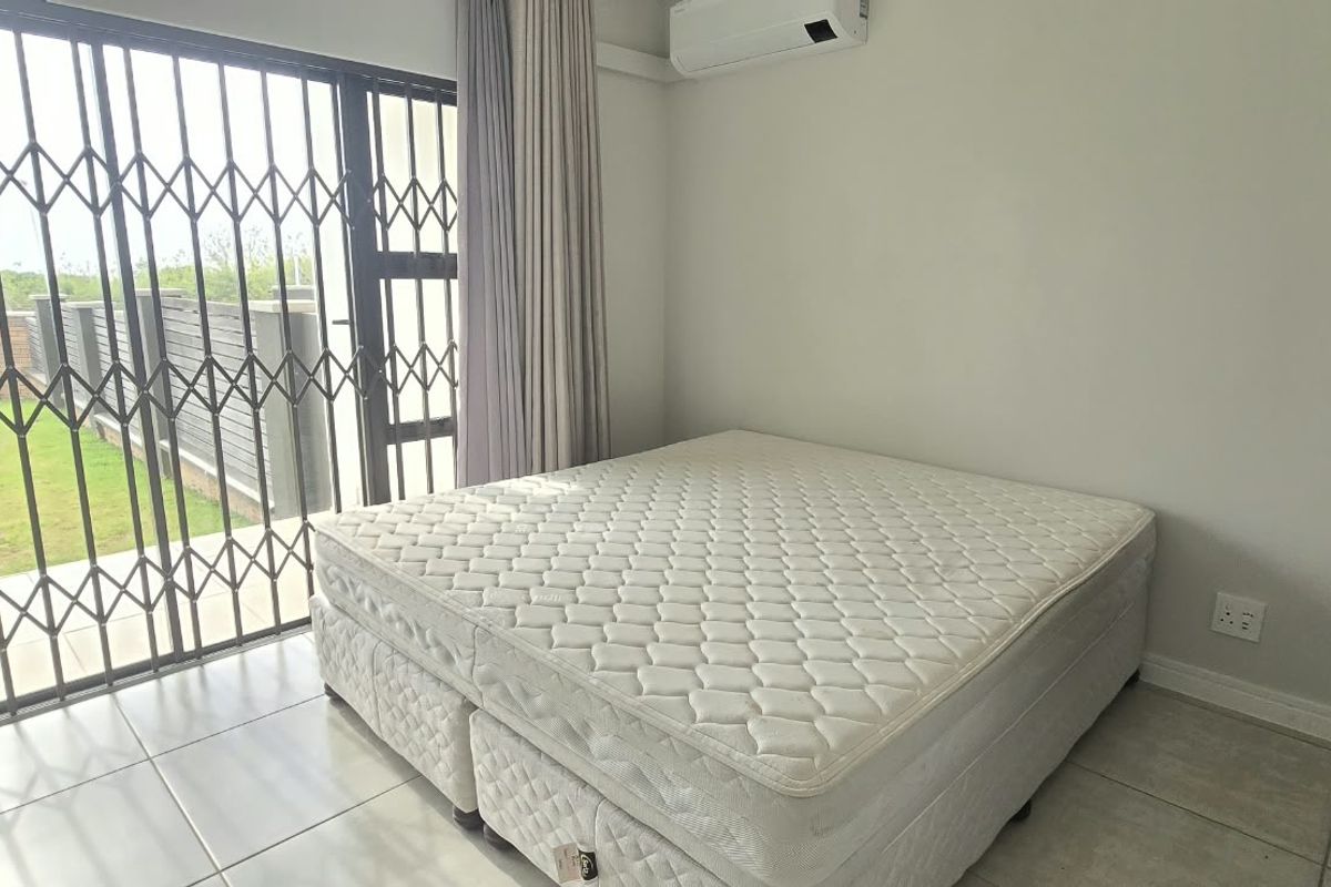 A bedroom featuring tiled flooring, an air conditioning unit, and a sliding door with a security gate leading to the exterior.