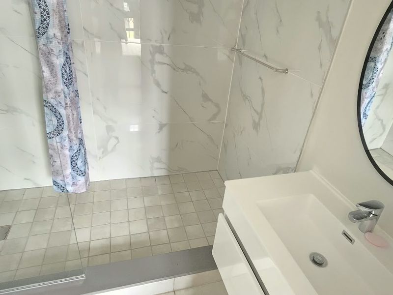 Modern bathroom featuring a walk-in shower with marble-look wall tiles, a sleek vanity unit with basin, and contemporary fixtures.