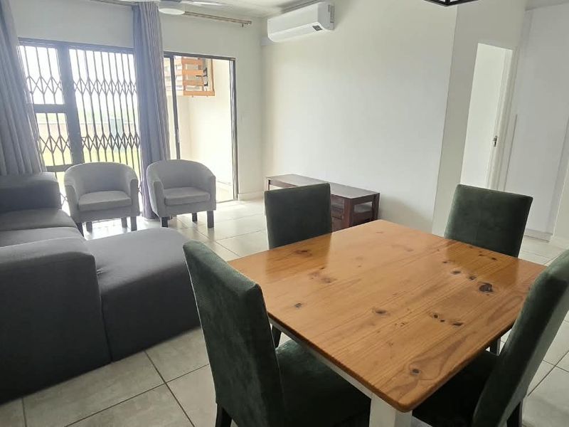 Open-plan living and dining area featuring tiled flooring, a ceiling fan, and a split-system air conditioner with access to an outdoor balcony.