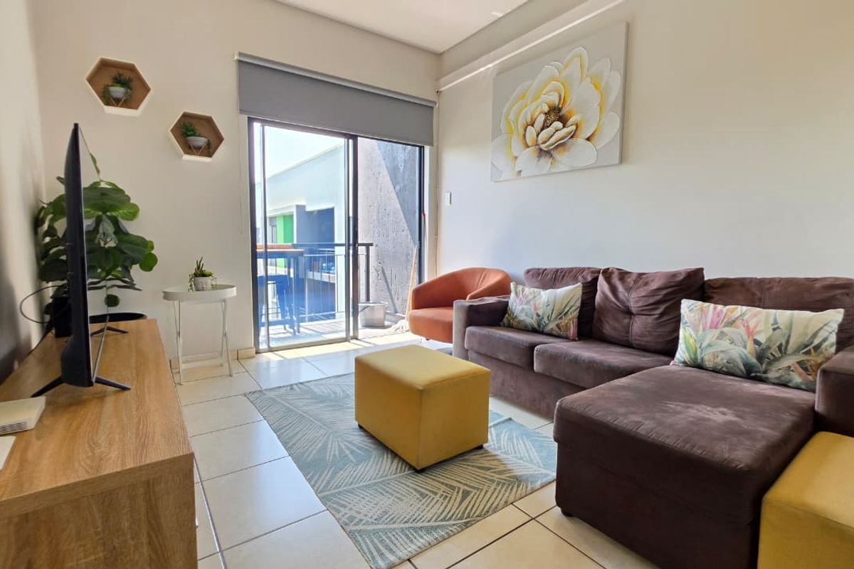 A bright living room featuring tiled flooring and a sliding glass door that provides access to an outdoor balcony area.