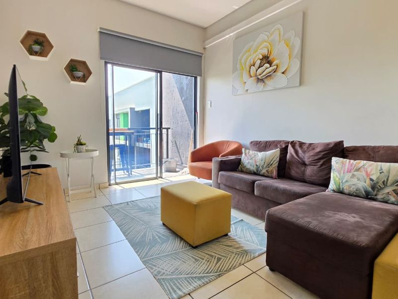 A bright living room featuring tiled flooring and a sliding glass door that provides access to an outdoor balcony area.