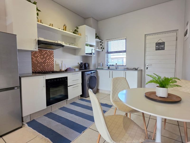 Open plan kitchen and dining area featuring modern white cabinetry, built-in oven, hob, extractor fan, and tiled flooring with integrated laundry space.