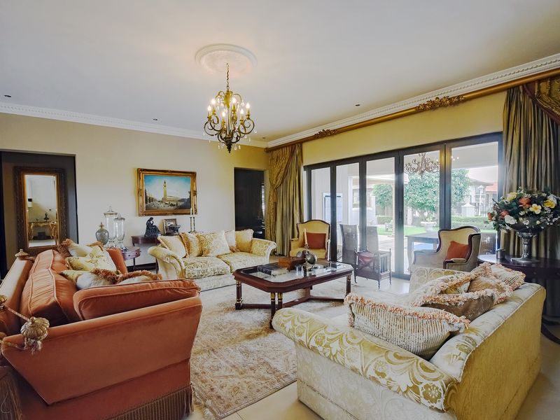 Spacious living room featuring elegant crown molding, a decorative ceiling rose with a chandelier, and large sliding glass doors providing access to the garden.