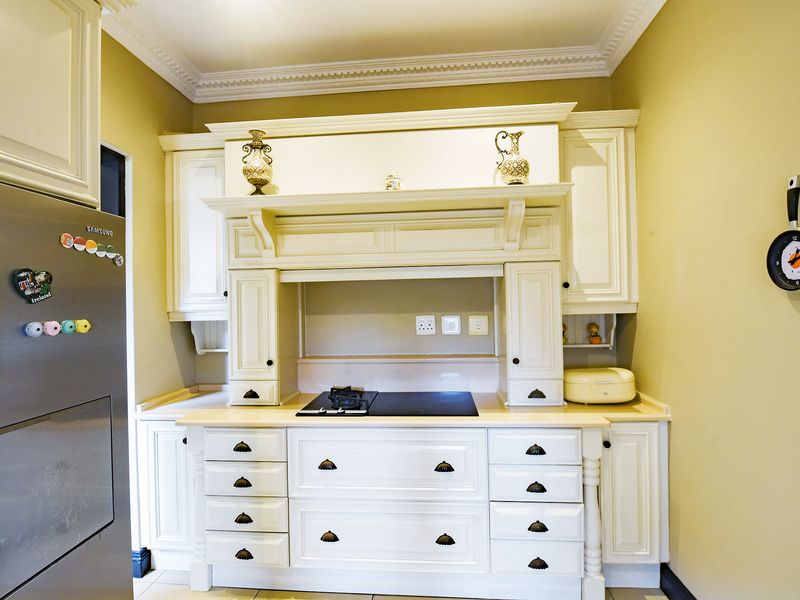A well-maintained kitchen featuring classic cream cabinetry, a built-in hob with an integrated extractor hood, and decorative crown molding.