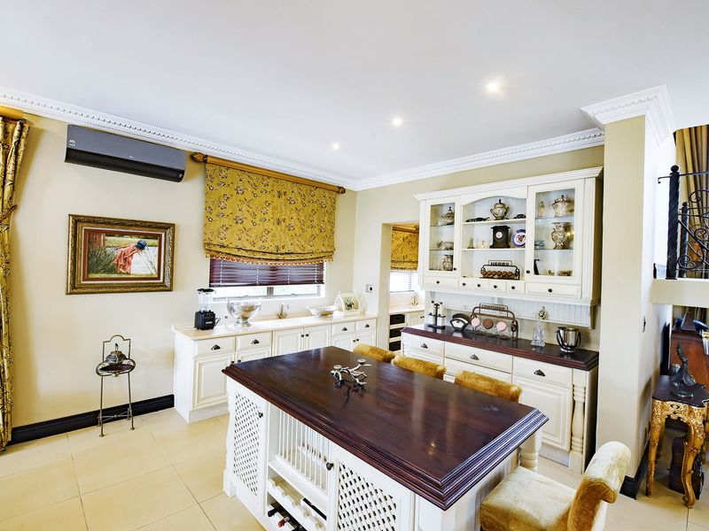 A well-maintained kitchen featuring classic white cabinetry, a dark wood-topped island, tiled flooring, and integrated air conditioning.