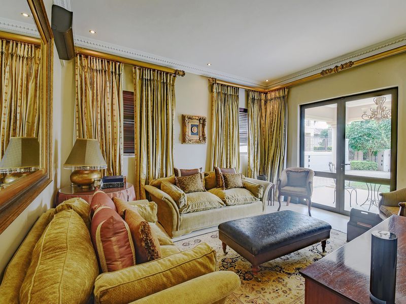 A well-maintained living room featuring elegant crown molding, recessed lighting, and large glass sliding doors providing access to the outdoor patio area.