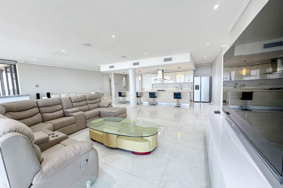 Spacious open-plan living area featuring polished porcelain tiles, recessed lighting, ducted air conditioning, and a modern kitchen with a central island.