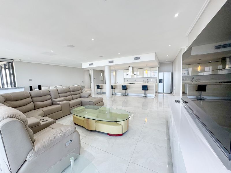 Spacious open-plan living area featuring polished porcelain tiles, recessed lighting, ducted air conditioning, and a modern kitchen with a central island.