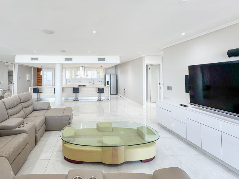 Spacious open-plan living area featuring a modern kitchen with a central island, sleek cabinetry, and high-quality tiled flooring throughout.