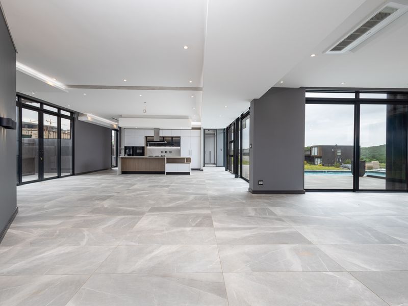 Spacious open-plan living and kitchen area featuring modern cabinetry, large format floor tiles, and expansive glass doors leading to the outdoor pool area.