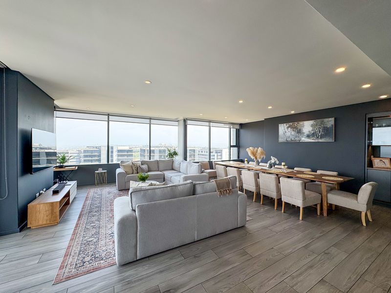 Spacious open-plan living and dining area featuring modern laminate flooring, recessed lighting, and expansive floor-to-ceiling windows offering panoramic urban views.
