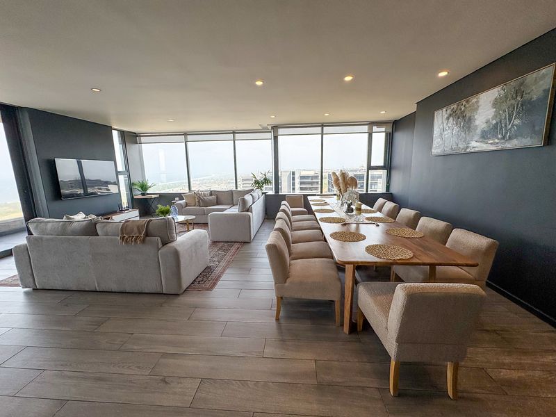 Spacious open-plan living and dining area featuring floor-to-ceiling windows with expansive views, modern tiled flooring, and recessed lighting.