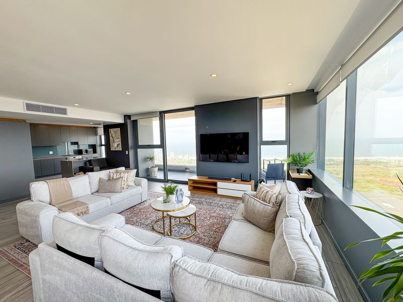 Spacious open-plan living area featuring floor-to-ceiling windows with panoramic views, modern kitchen cabinetry, and integrated ducted air conditioning.