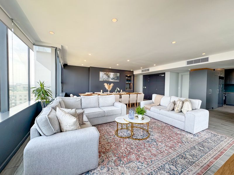 Spacious open-plan living and dining area featuring modern tiled floors, recessed lighting, ducted air conditioning, and expansive windows with natural light.