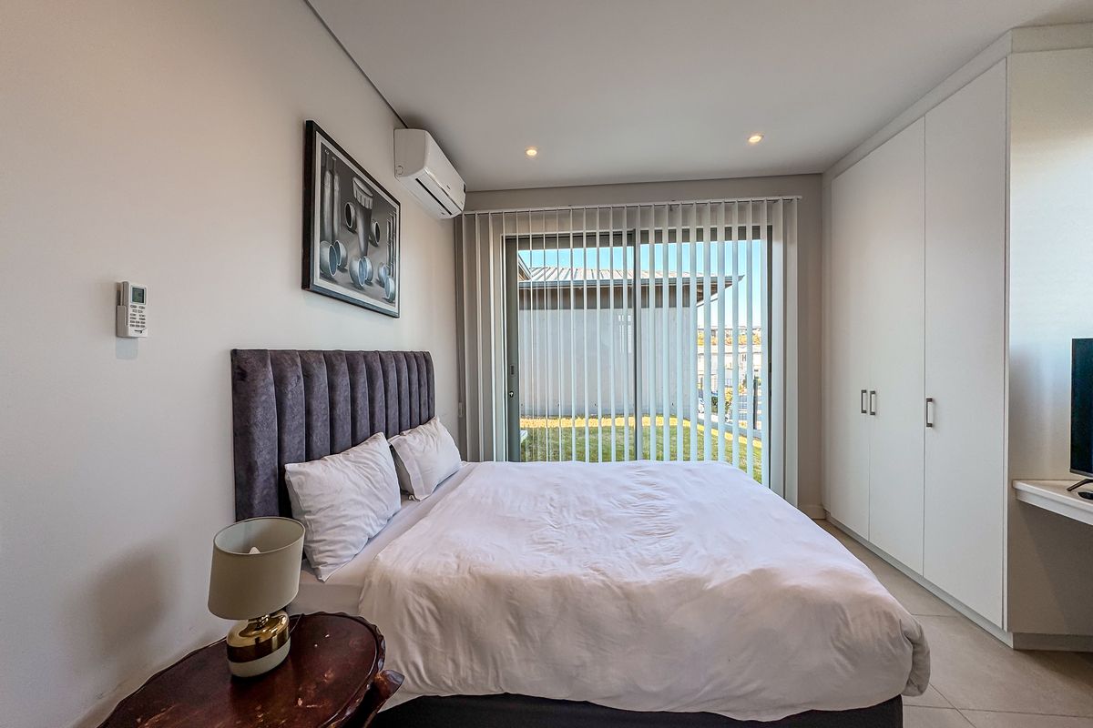 Modern bedroom featuring built-in cupboards, tiled flooring, split-system air conditioning, and a sliding glass door providing access to the exterior.
