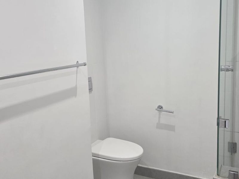 A clean, modern bathroom featuring a wall-mounted toilet, glass shower enclosure, and chrome fixtures.