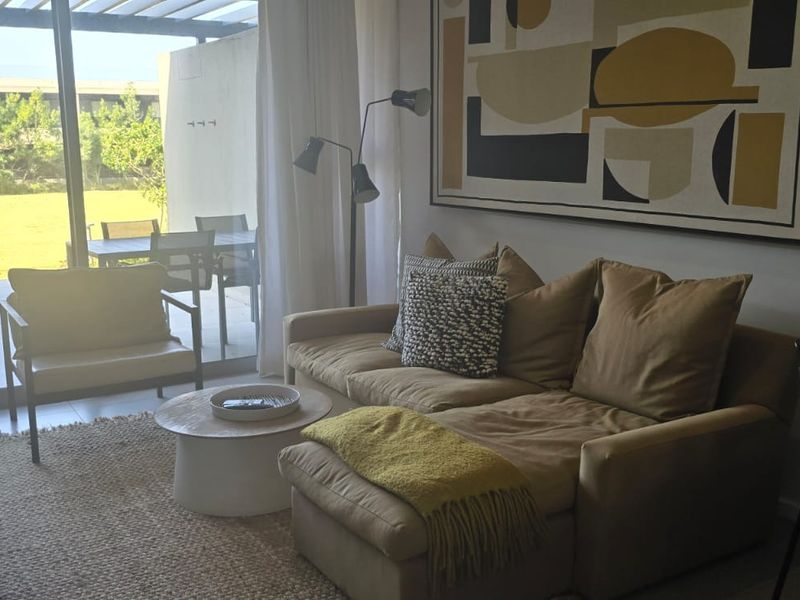 A bright living room featuring large sliding glass doors that open onto a covered patio, providing seamless indoor-outdoor flow and natural light.