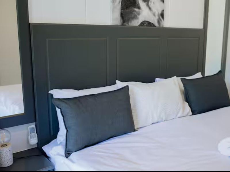 A well-maintained bedroom featuring a custom dark-toned built-in headboard and an integrated wall mirror.