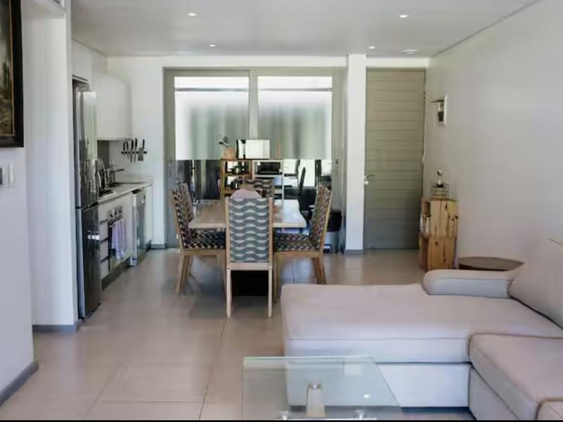 An open-plan living and dining area featuring tiled flooring, recessed lighting, and a modern kitchen with integrated cabinetry and appliances.