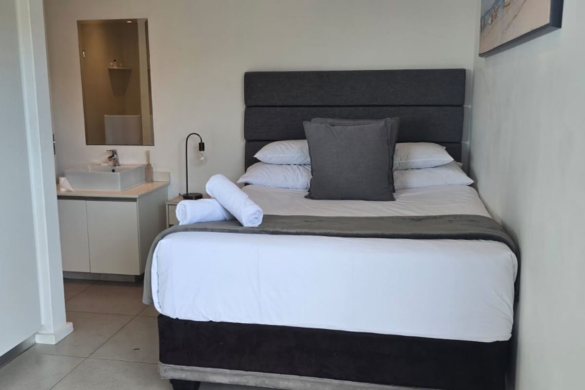A compact bedroom featuring a built-in wardrobe and an integrated vanity basin area with tiled flooring.