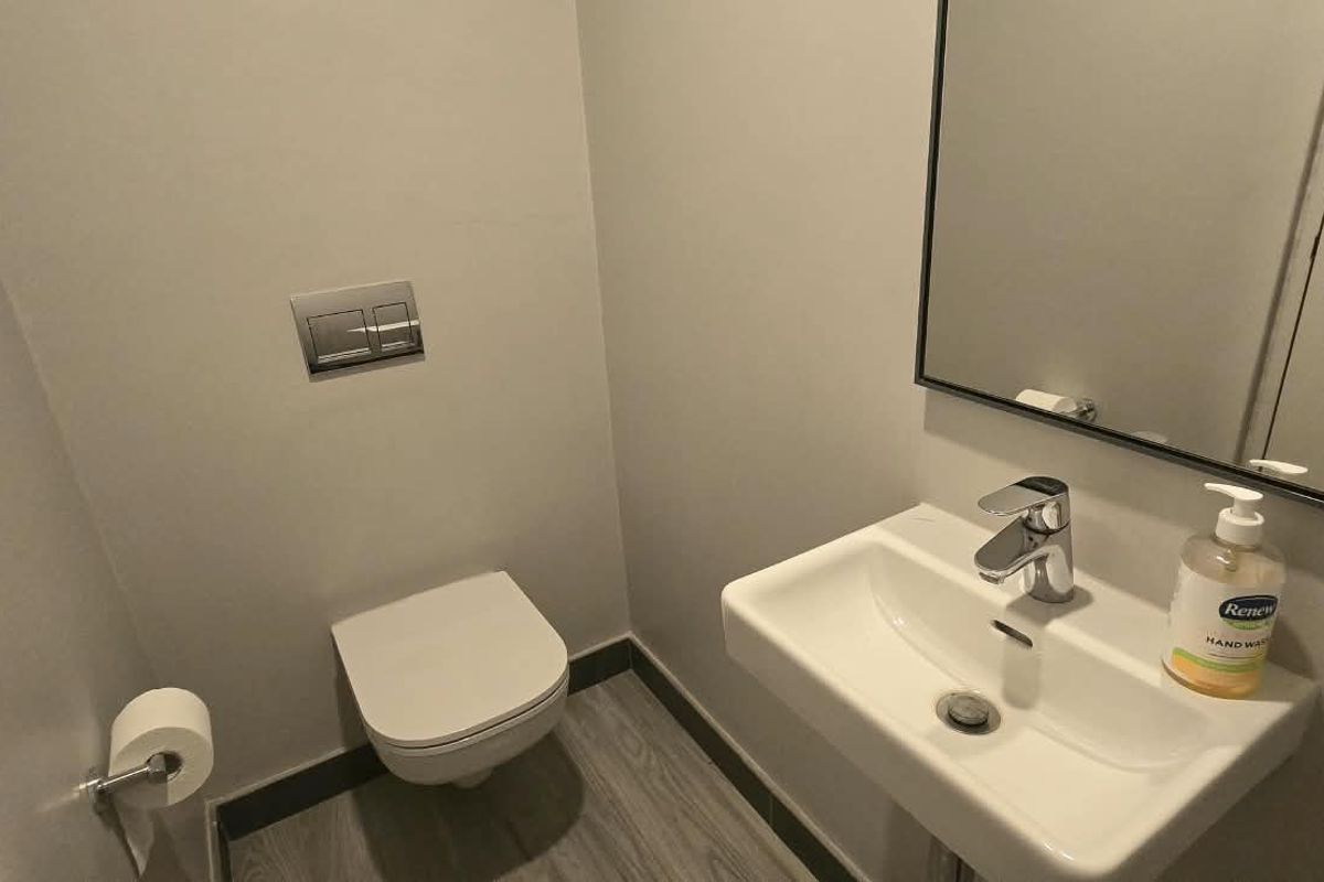 A modern, compact guest bathroom featuring a wall-mounted toilet with a concealed cistern and a sleek wall-mounted basin with chrome fixtures.