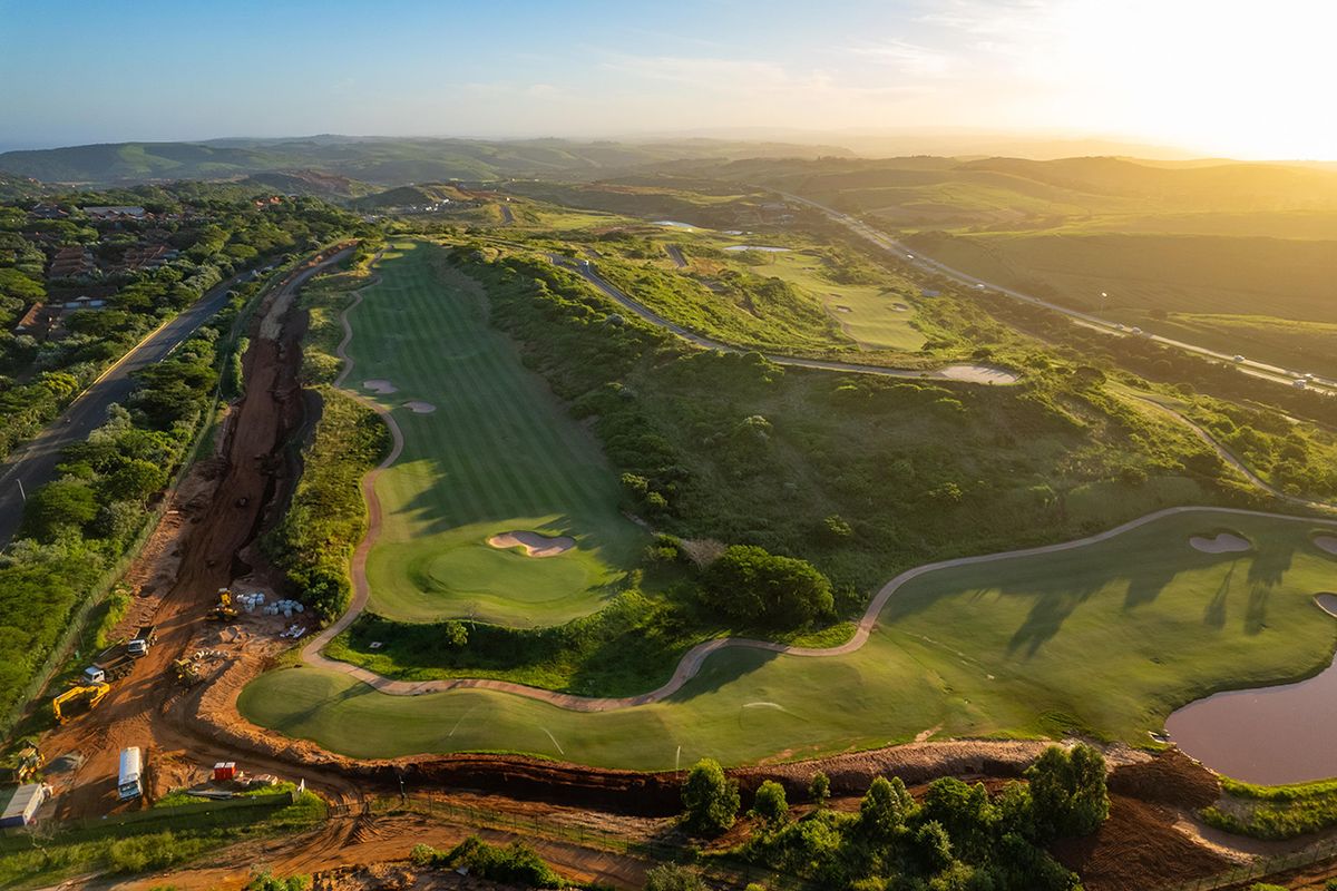 An aerial view of a residential golf estate development featuring manicured fairways, natural landscape, and ongoing site preparation work.