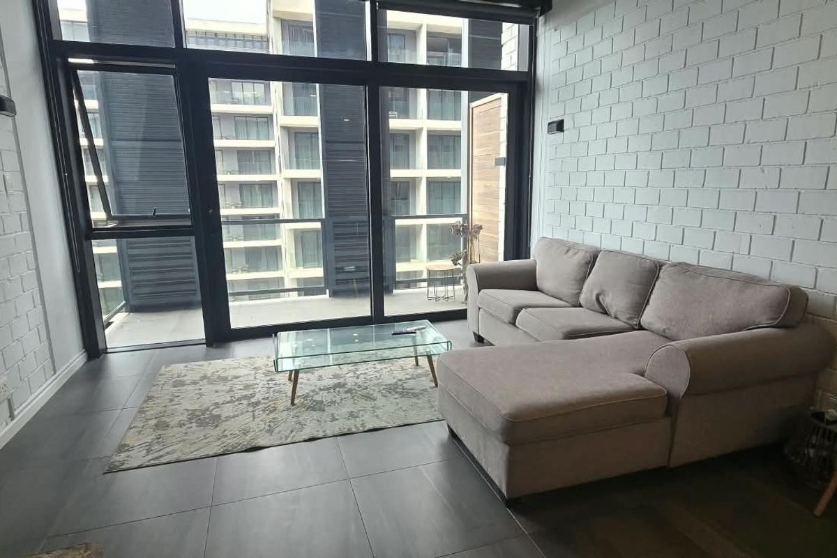 Modern living room featuring exposed white brick walls, large glass sliding doors providing natural light, and dark tiled flooring.