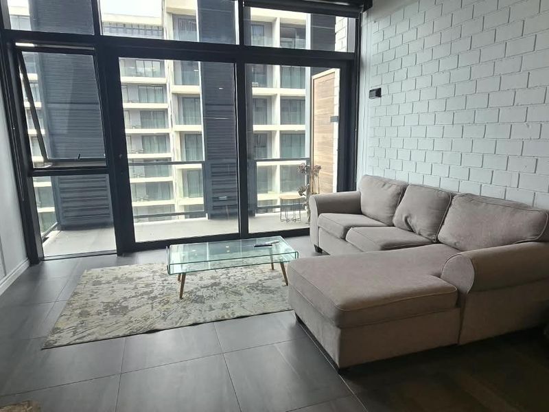 Modern living room featuring exposed white brick walls, large glass sliding doors providing natural light, and dark tiled flooring.