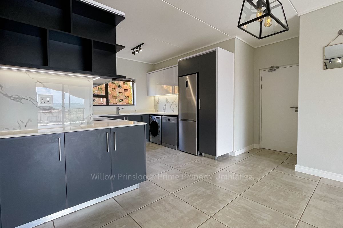 Modern kitchen featuring sleek dark cabinetry, stone countertops, marble-look splashbacks, and integrated space for appliances, finished with neutral floor tiles.