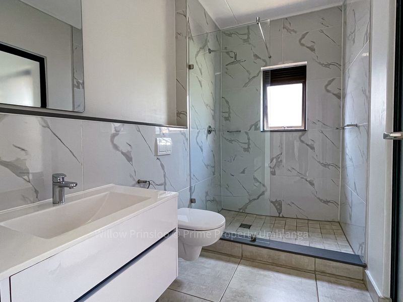 Modern bathroom featuring a wall-mounted vanity, walk-in shower with glass screen, and elegant marble-look wall tiling.