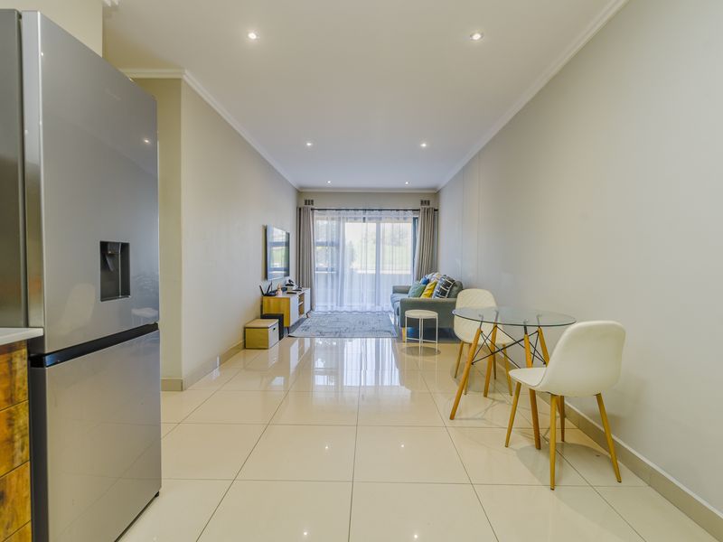 An open-plan living and dining area featuring polished tile flooring, recessed lighting, and a sliding glass door leading to an outdoor space.