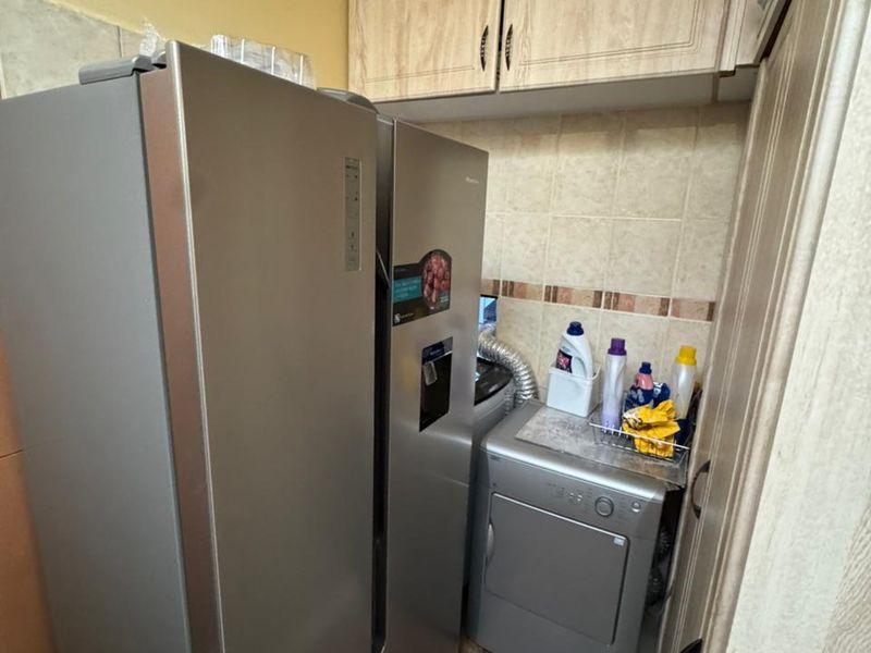 Compact laundry area featuring built-in overhead cabinetry and tiled backsplash, providing functional storage and utility space.