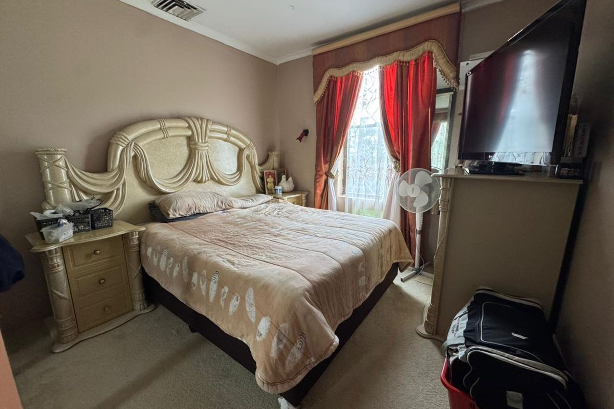 A standard bedroom featuring carpeted flooring and a ducted air conditioning vent, providing a functional and comfortable living space.