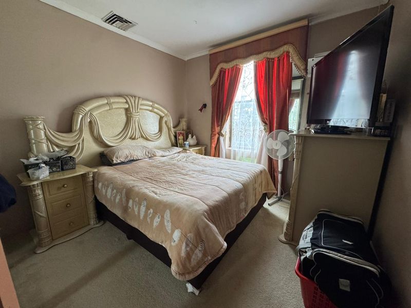 A standard bedroom featuring carpeted flooring and a ducted air conditioning vent, providing a functional and comfortable living space.