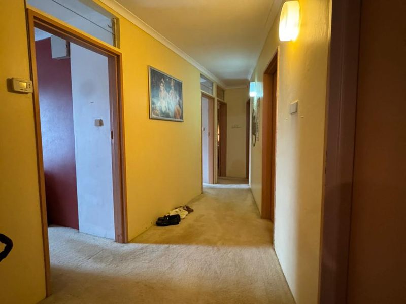 A functional hallway featuring carpeted flooring, coved ceilings, and multiple doorways leading to various rooms within the home.