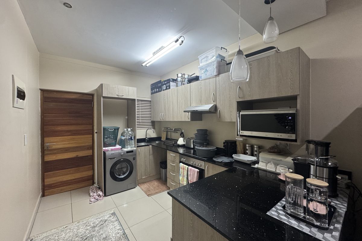 A functional kitchen featuring wood-finish cabinetry, black granite countertops, integrated appliances, and tiled flooring, providing a practical and well-organized culinary space.