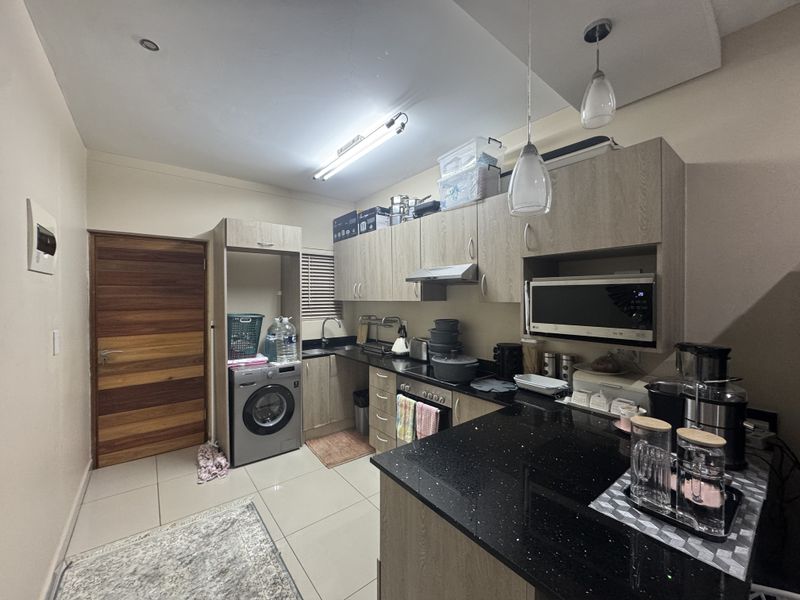 A functional kitchen featuring wood-finish cabinetry, black granite countertops, integrated appliances, and tiled flooring, providing a practical and well-organized culinary space.