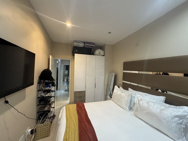 A bedroom featuring tiled flooring, recessed downlighting, and a built-in wardrobe with integrated storage.