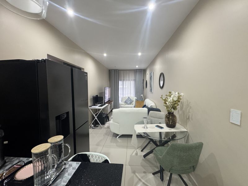 Open-plan living and dining area featuring tiled flooring, recessed downlighting, and access to a balcony through sliding glass doors.