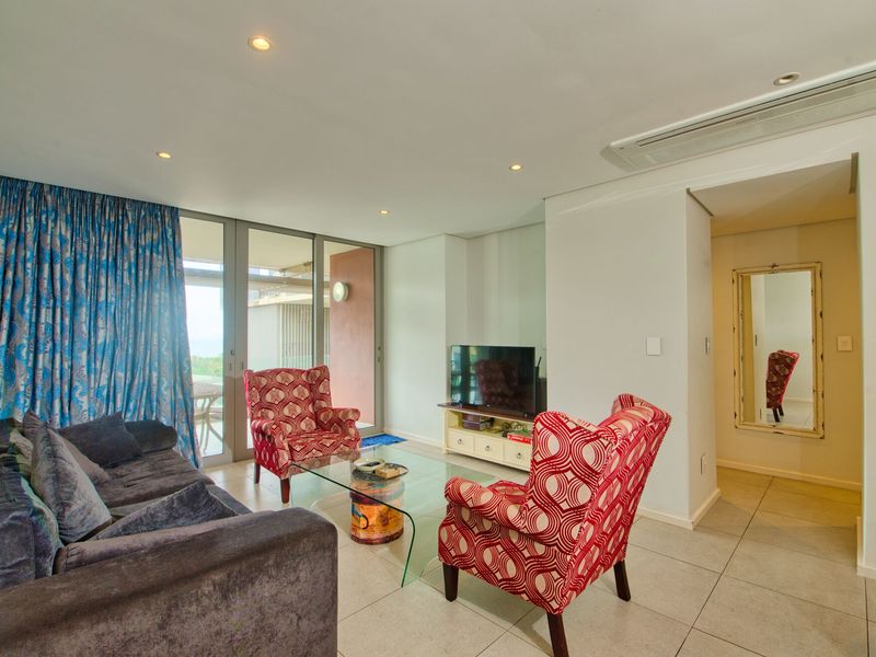 A bright living room featuring tiled flooring, recessed lighting, ducted air conditioning, and large sliding glass doors leading to an outdoor area.