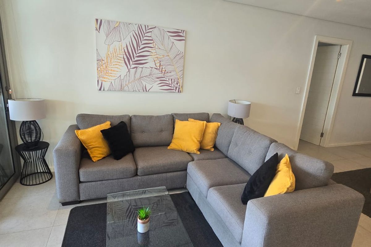 A well-maintained living room featuring neutral tiled flooring, recessed lighting, and large sliding glass doors providing access to an outdoor area.