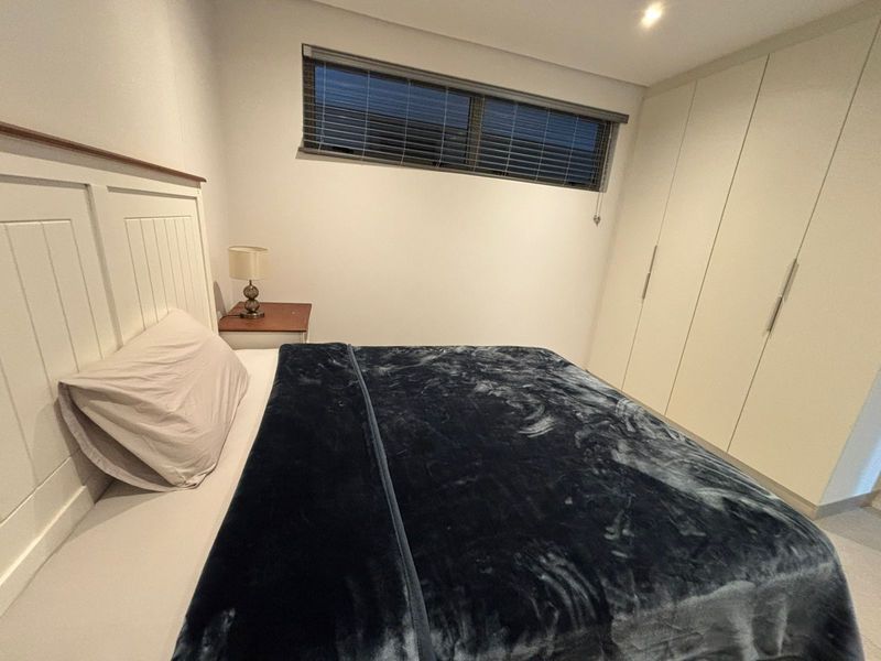 A well-maintained bedroom featuring built-in cupboards, recessed downlighting, and venetian blinds, offering a clean and functional living space.
