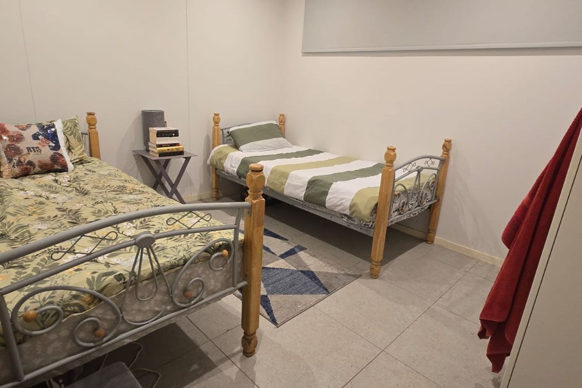A functional bedroom featuring tiled flooring and a built-in wardrobe, providing a practical space for residents.