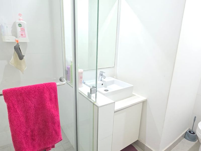 A modern, compact bathroom featuring a glass-enclosed shower, a sleek vanity basin with storage, and a wall-hung toilet with a concealed cistern.