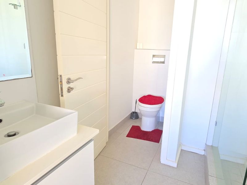 A clean, modern bathroom featuring a vanity basin, a separate shower enclosure with glass door, and a wall-mounted toilet.