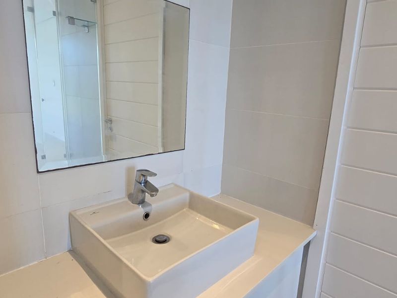 A clean, modern bathroom vanity area featuring a contemporary vessel sink, chrome mixer tap, and a large wall-mounted mirror.